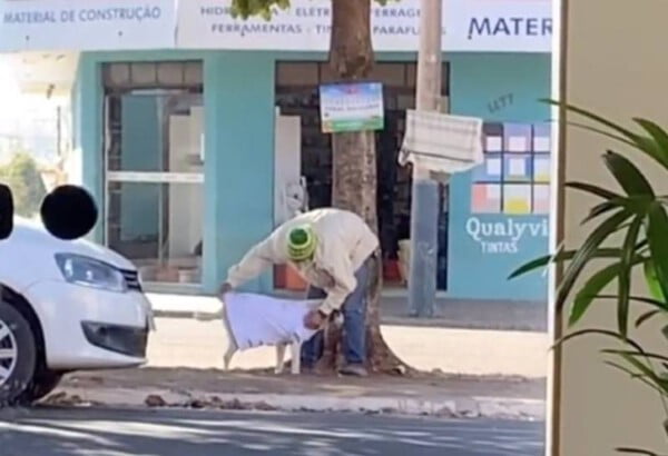 Homem se aproxima de cachorra de rua e a agasalha para protegê-la do frio com roupa de varal solidário morador-de-rua-cuida-de-cachorra-sem-teto