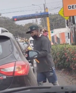 Jovem carrega seu cachorro nas costas enquanto limpa carros nas ruas para sobreviver