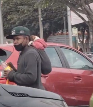 Jovem carrega seu cachorro nas costas enquanto limpa carros nas ruas para sobreviver